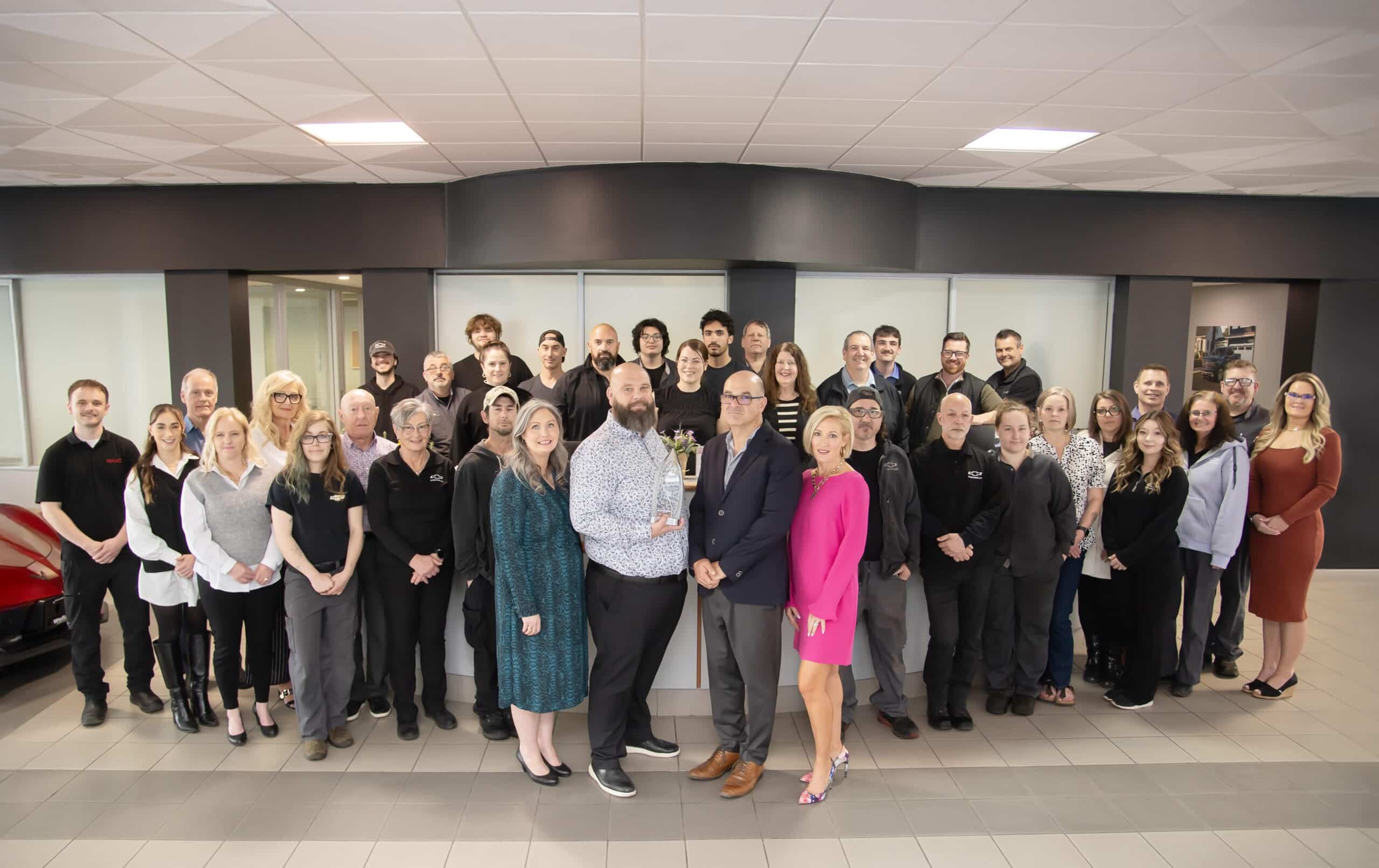 Group photo of a diverse team celebrating a company achievement in a modern office environment, featuring employees posing with an award, showcasing teamwork and professionalism.