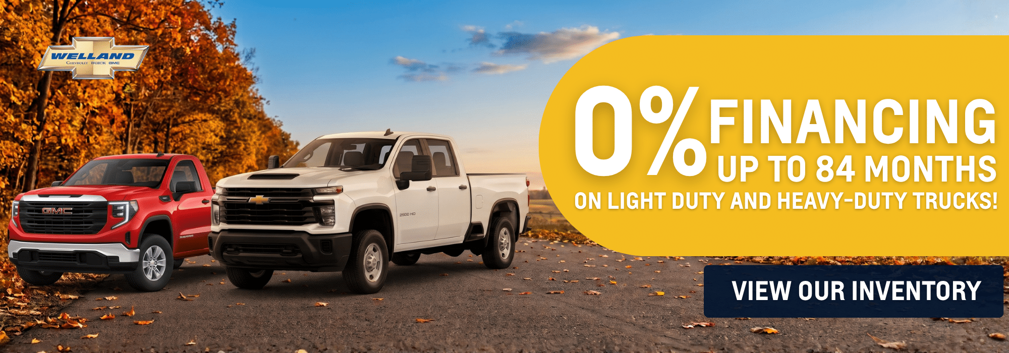 Two trucks on a forest road with fall foliage and text promoting 0% financing for light and heavy-duty trucks.