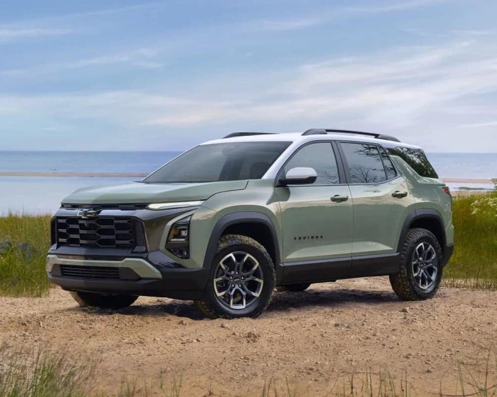 2023 Chevrolet Equinox parked in a sandy area with grass, showcasing its sleek design and off-road capabilities, ideal for outdoor adventures.