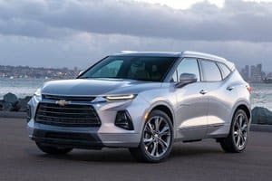 Silver Chevrolet Blazer SUV parked by the waterfront, showcasing its modern design and sleek profile against a cloudy sky.