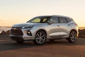 Silver Chevrolet Blazer SUV parked by the seaside at sunset, showcasing its modern design and sleek profile.