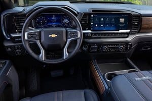 Interior view of a modern Chevrolet truck showcasing the dashboard, steering wheel, and advanced infotainment system with a large touchscreen display and wood accents.