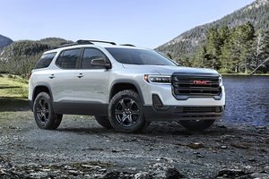 Modern GMC Acadia SUV parked by a scenic mountain lake, showcasing its rugged design and off-road capabilities. Ideal for outdoor adventures and family road trips.