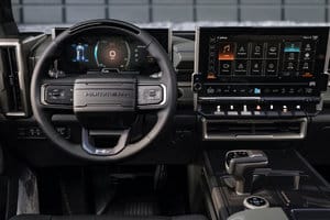 Interior view of a modern electric vehicle showcasing a sleek dashboard with a digital instrument cluster and a large touchscreen display, featuring controls for navigation, climate, and entertainment systems. The steering wheel is designed for ergonomic comfort, emphasizing a high-tech driving experience.