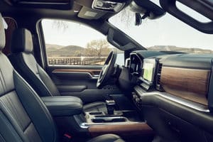 Luxury pickup truck interior showcasing high-quality leather seats, modern dashboard, and advanced infotainment system against a scenic outdoor backdrop. Ideal for showcasing automotive craftsmanship and comfort in vehicle advertisements.