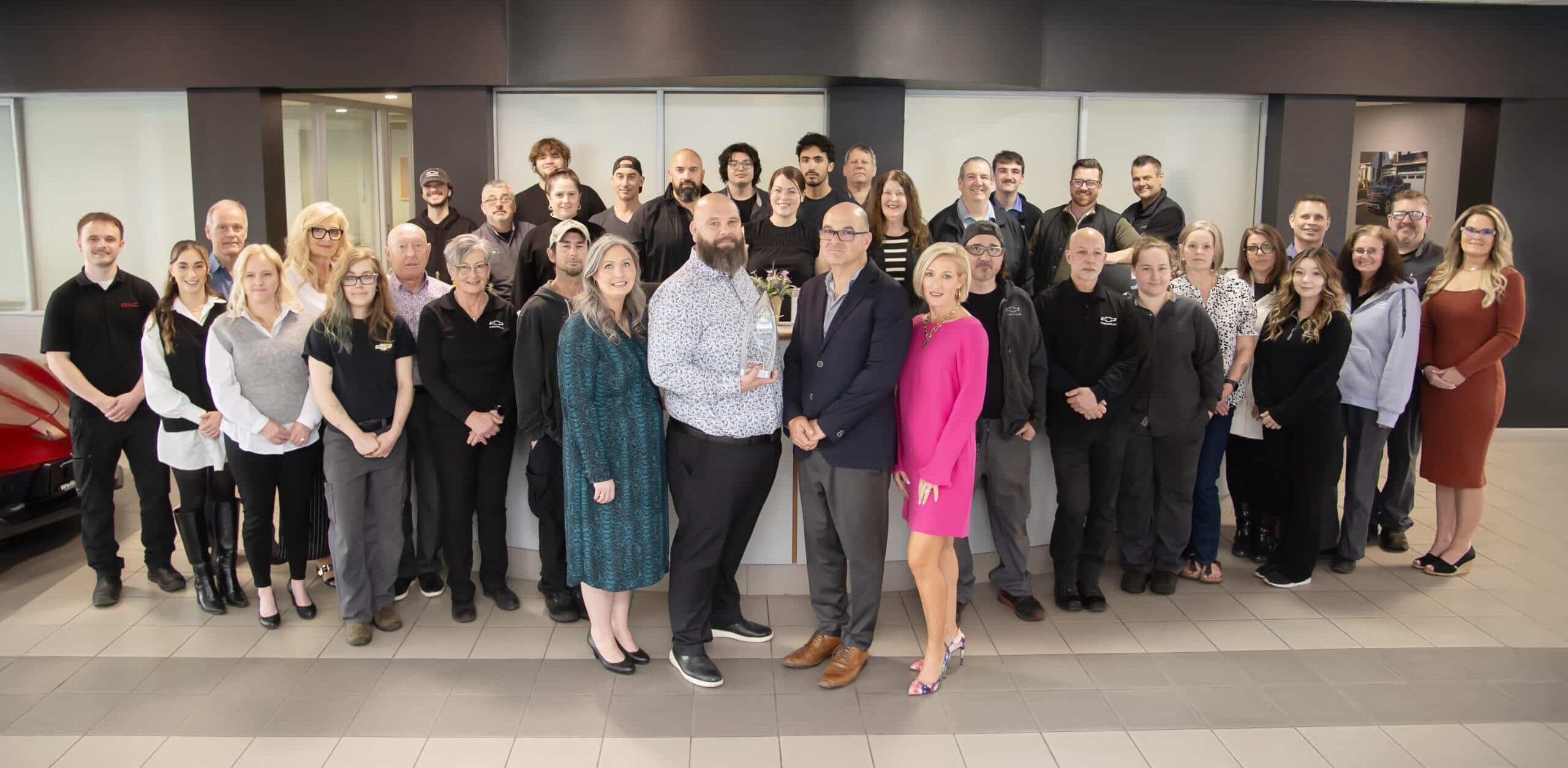 Group photo of a diverse team celebrating a company achievement in a modern office environment, featuring employees posing with an award, showcasing teamwork and professionalism.