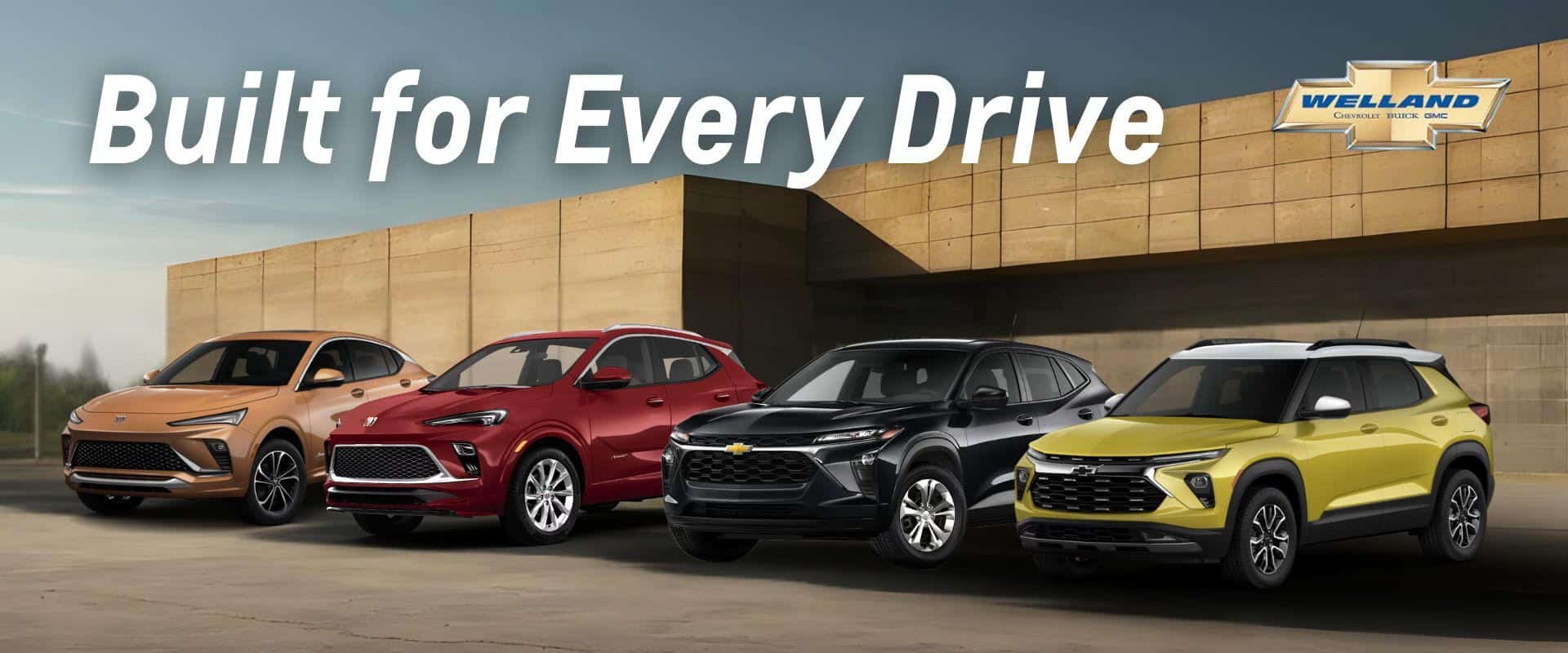 A lineup of four modern SUVs from Buick and Chevrolet displayed outdoors against a contemporary architectural backdrop. The vehicles stand in a row, showcasing their diverse colors and designs, emphasizing the theme "Built for Every Drive." This image highlights the versatility and style of the latest models available at Welland Chevrolet Buick GMC.