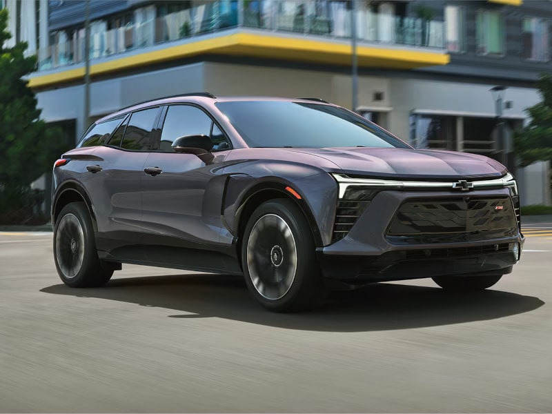 Modern Chevrolet SUV in motion, showcasing sleek design and advanced features, parked in an urban setting with contemporary architecture in the background.