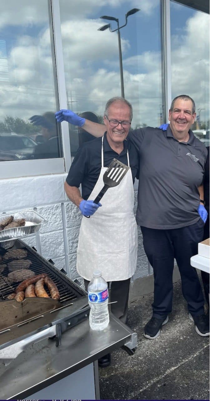 Two smiling team members grilling at a Welland Chevrolet staff BBQ